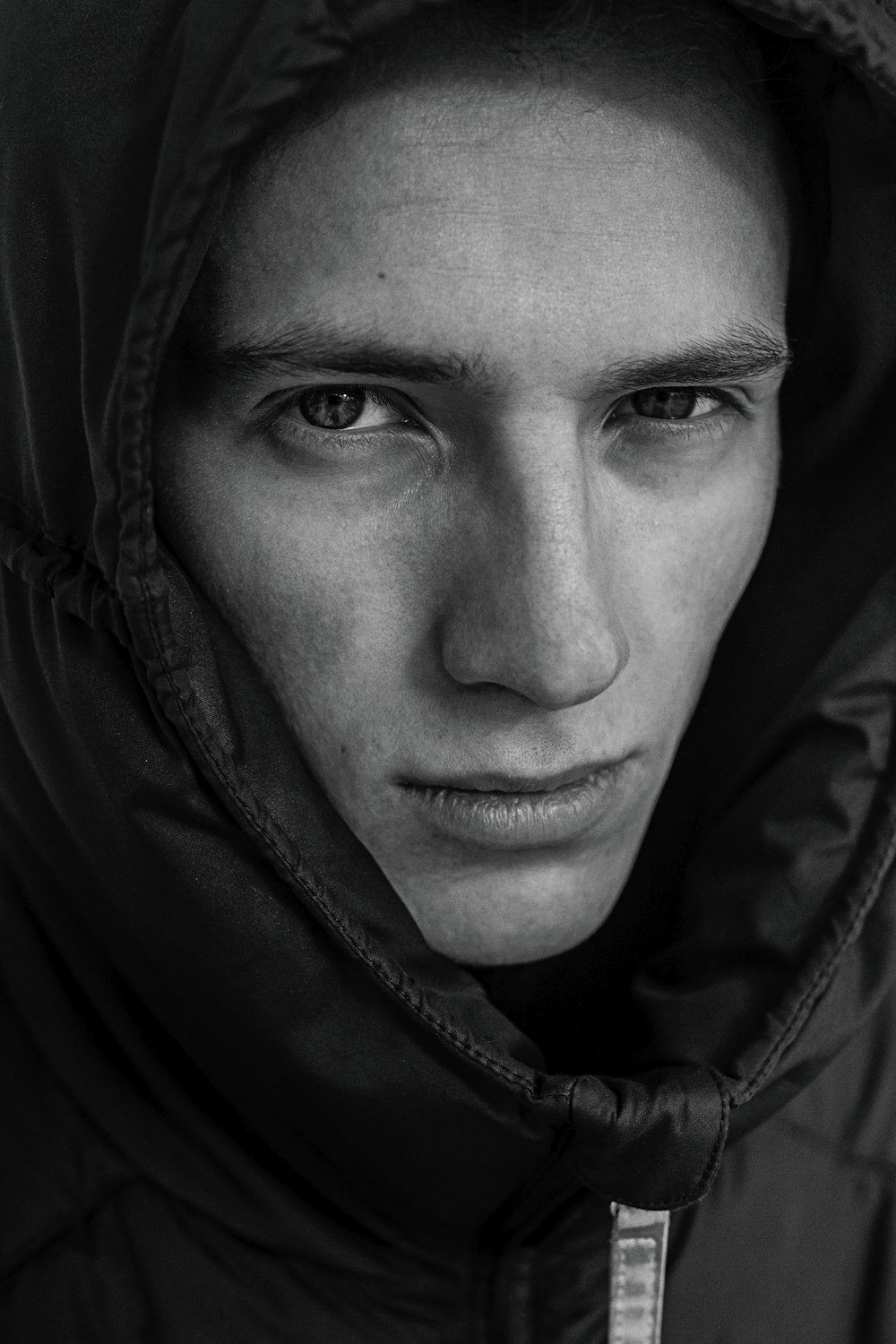 a black and white photo of a man in a hooded jacket