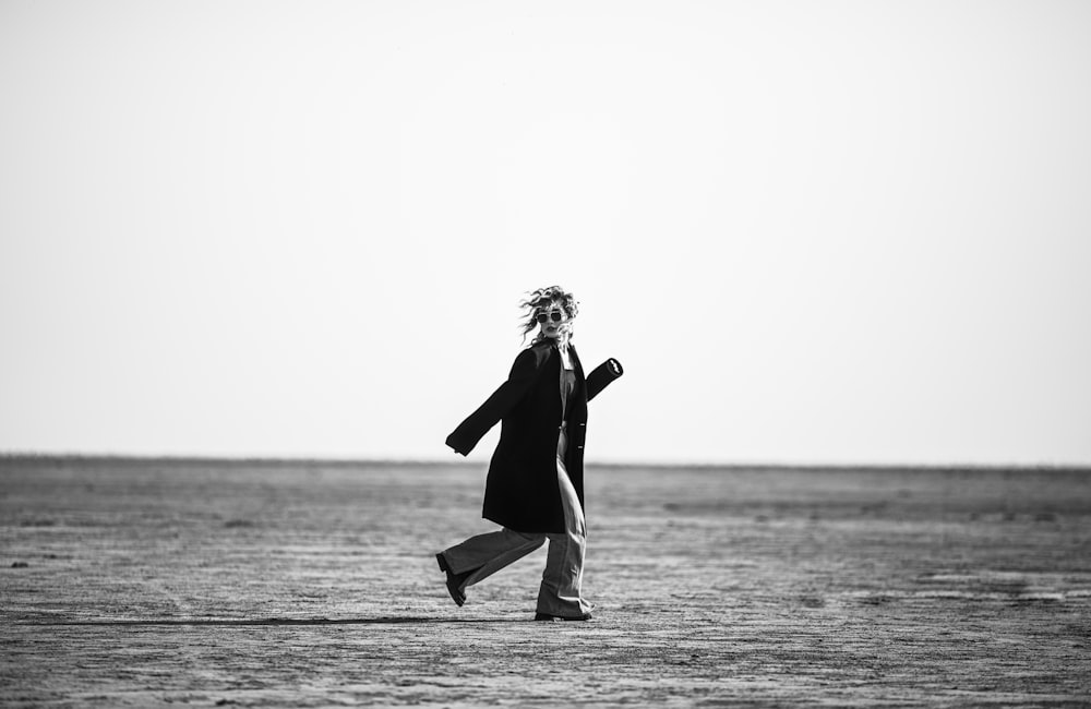 a woman walking across a beach next to the ocean