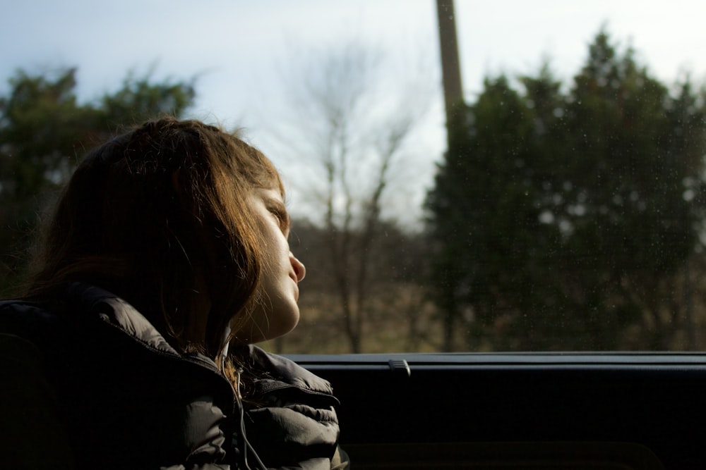 a young girl sitting in a car looking out the window