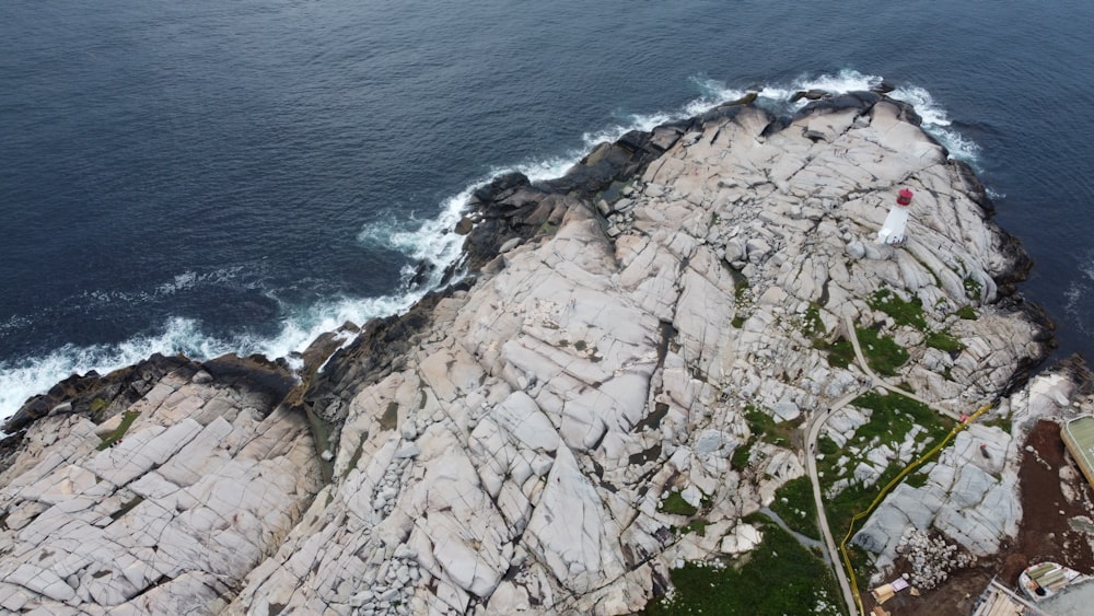 an aerial view of a rocky coastline with a person standing on top of it
