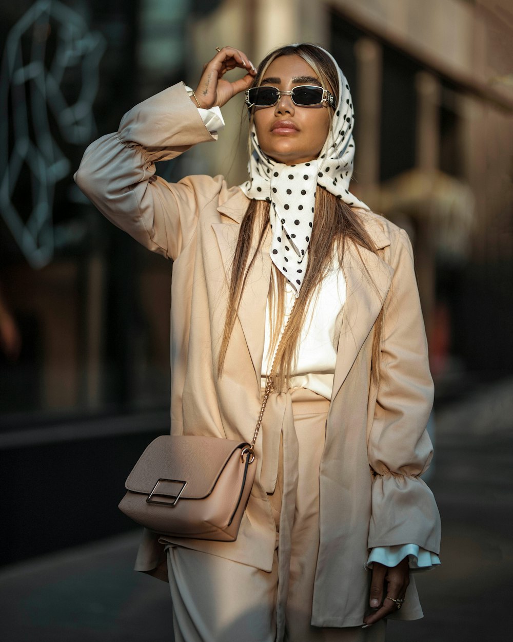 a woman in a trench coat and polka dot scarf