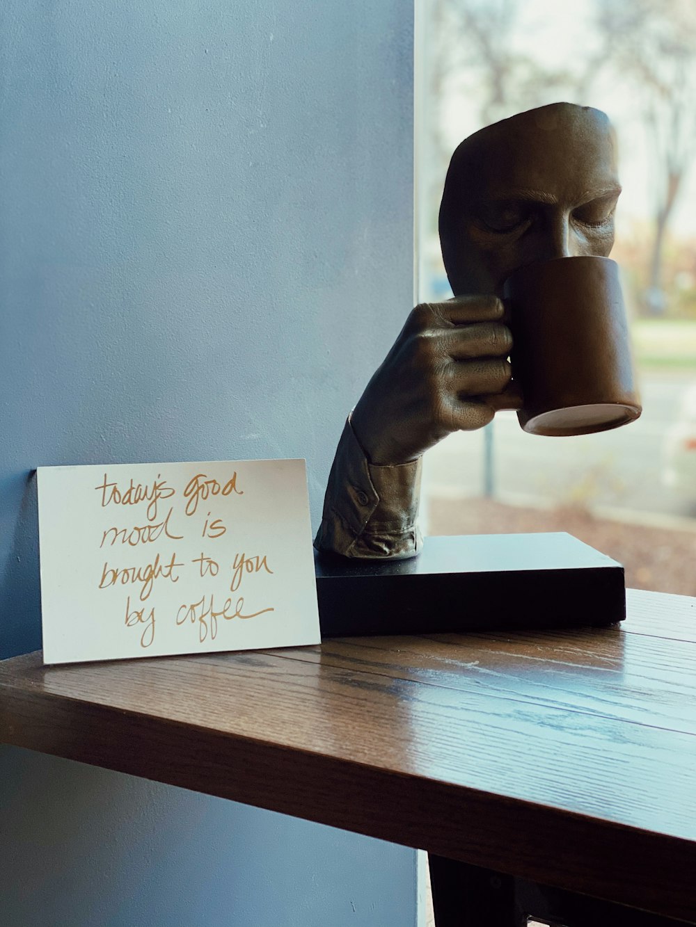 eine Statue einer Person, die eine Tasse Kaffee hält