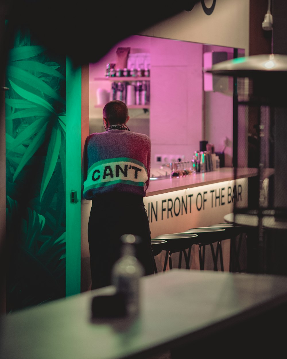 a man standing in front of a bar wearing a hat