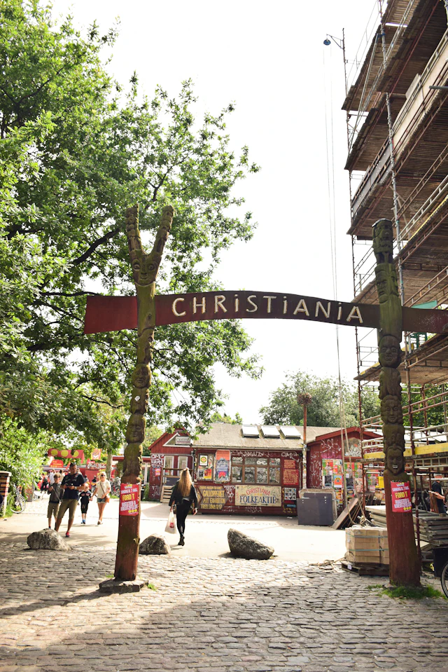 The wooden 'Christiania' entrance sign arching over the cobbled path into Freetown Christiania