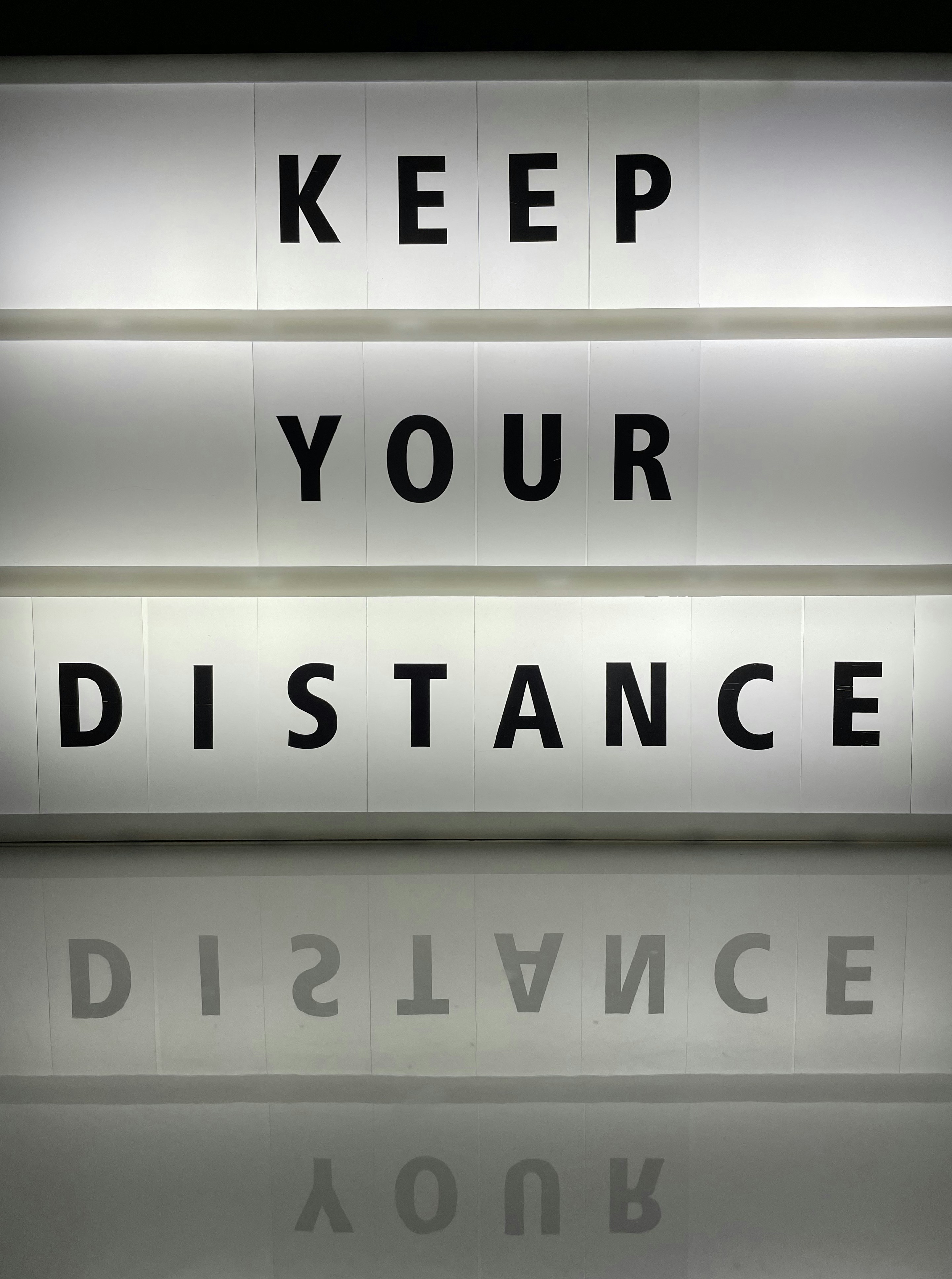 a lighted sign that says keep your distance