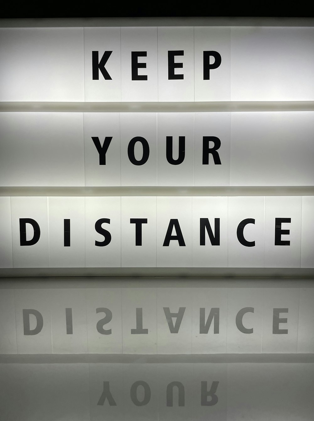 a lighted sign that says keep your distance