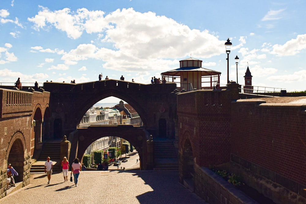 a couple of people walking down a street next to a bridge