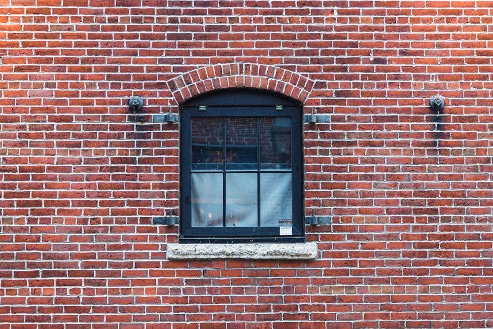 a brick wall with a window and a bench