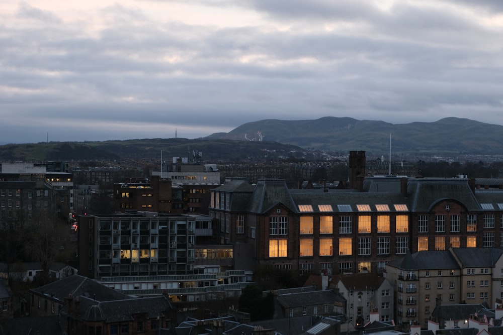 a view of a city at dusk with mountains in the background