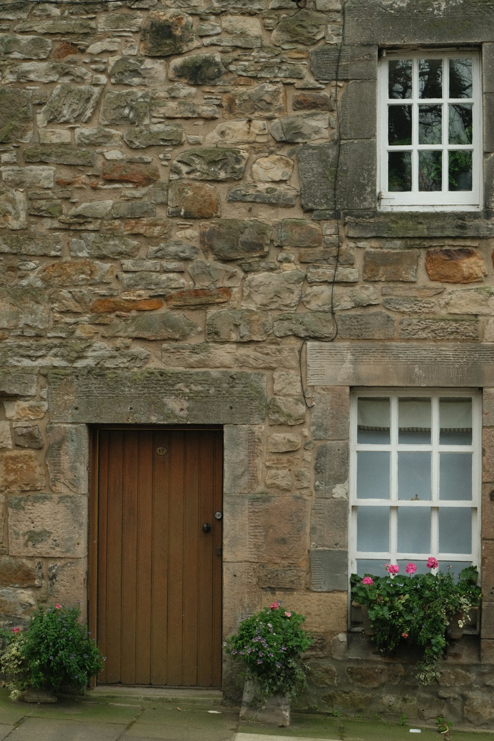 a stone building with a brown door and two windows