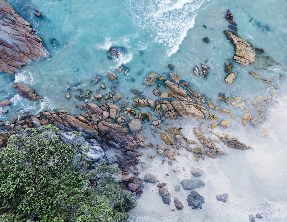 an aerial view of a beach with rocks and water