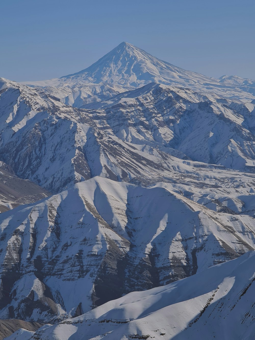 a mountain range covered in snow under a blue sky