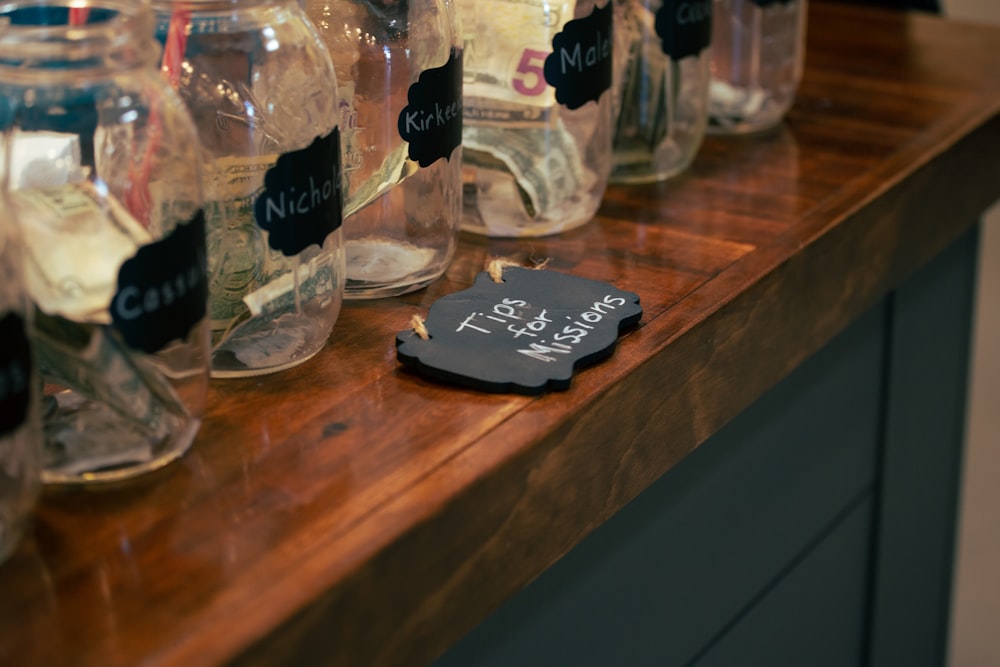 a wooden counter topped with lots of jars filled with liquid