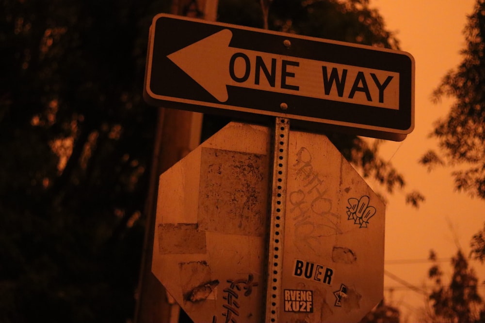 a one way street sign with graffiti on it