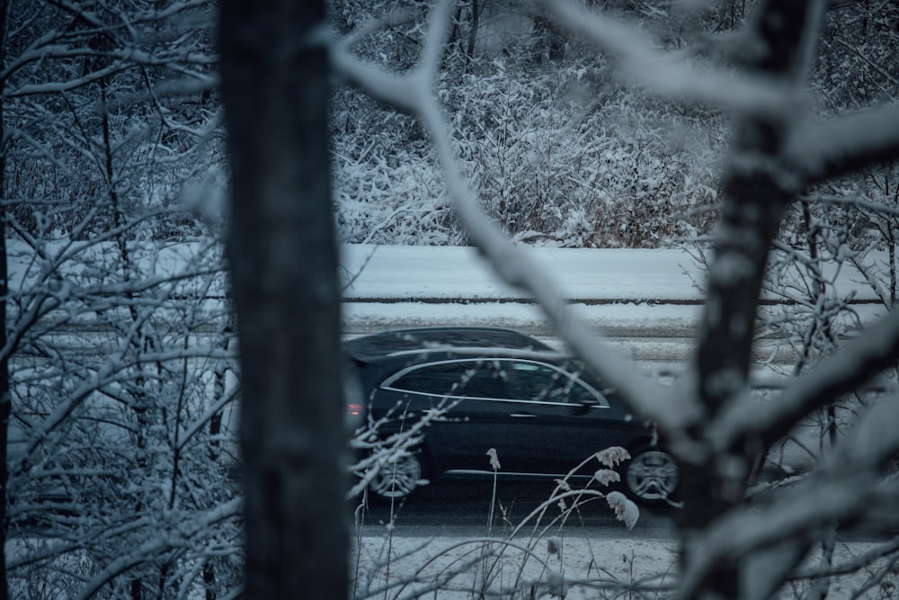Un coche negro conduciendo por una carretera cubierta de nieve