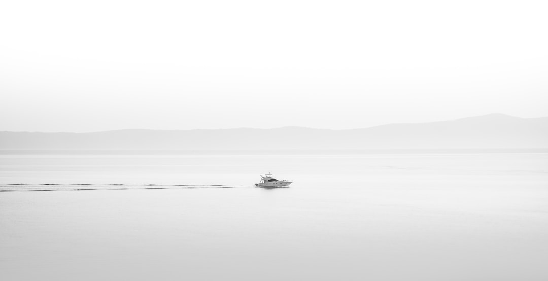 a small boat floating on top of a large body of water, One horizontal ship.