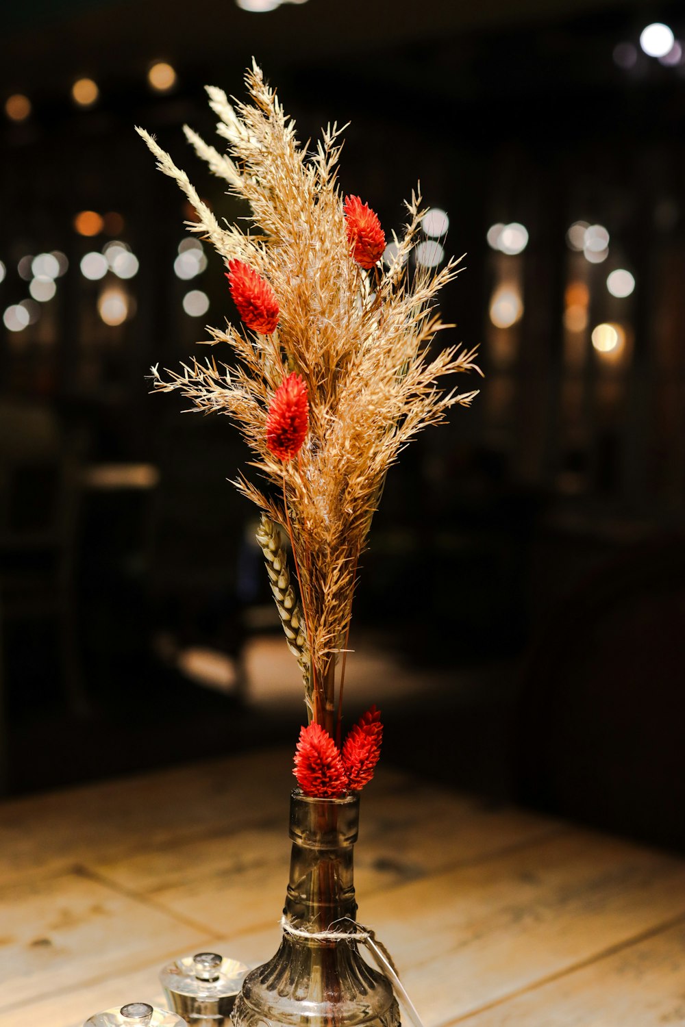 a vase filled with red flowers on top of a wooden table