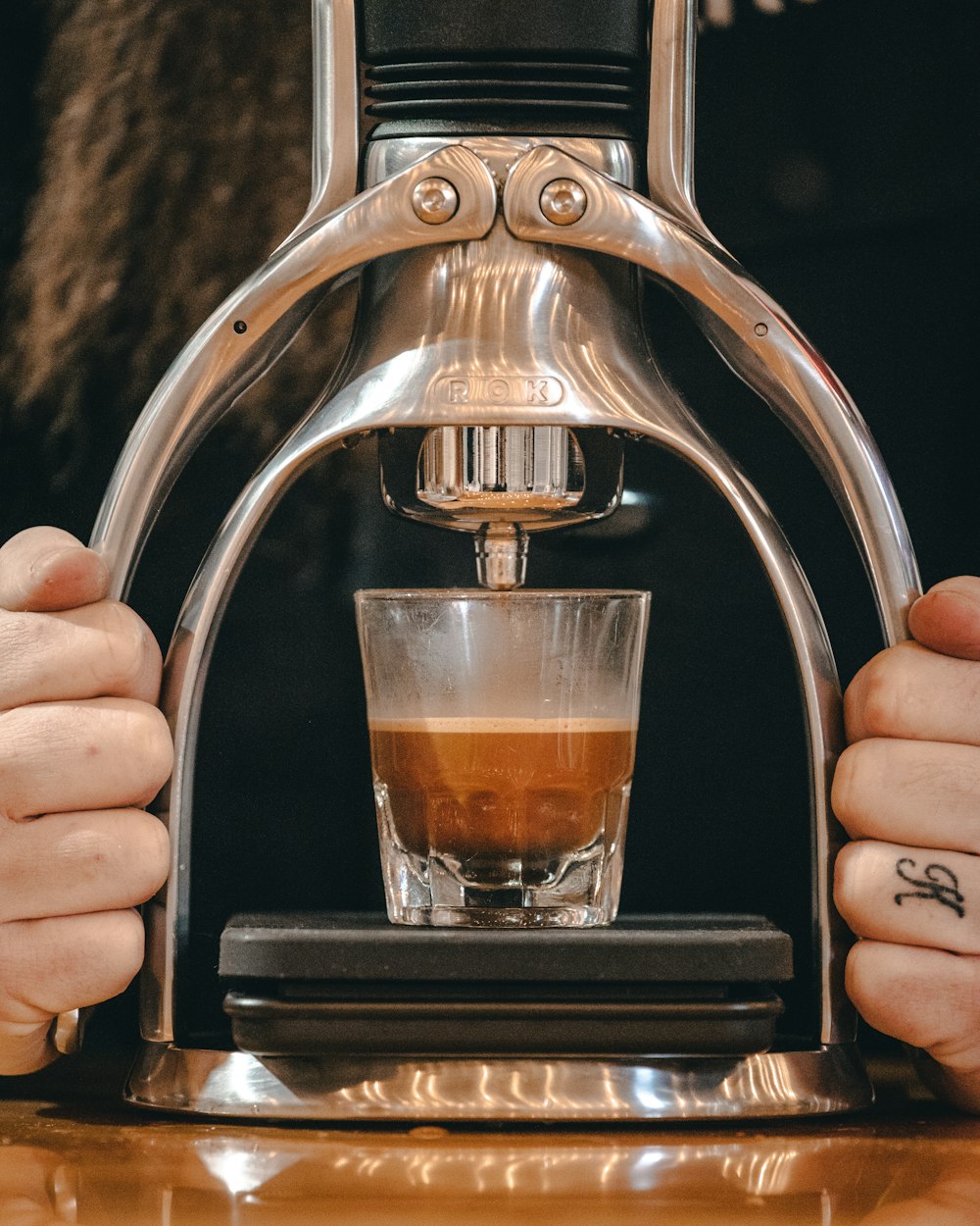 a person holding a cup of coffee in front of a machine