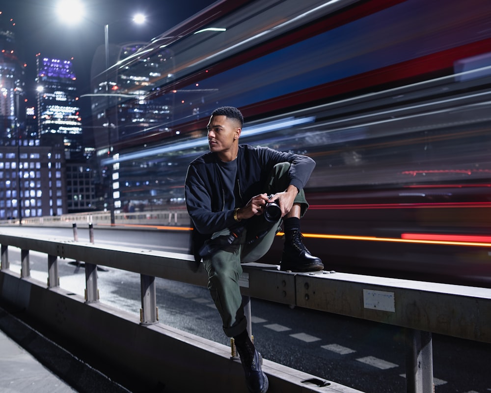 a man sitting on a rail in front of a city skyline