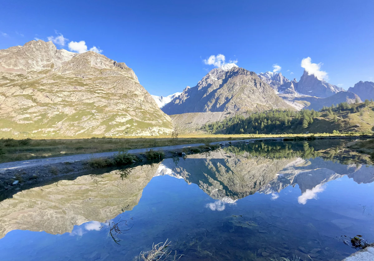 Rocky peaks near Courmayeur reflected in a still mountain lake under a blue sky