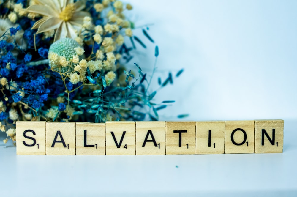 a wooden block that says salvation next to a bouquet of flowers