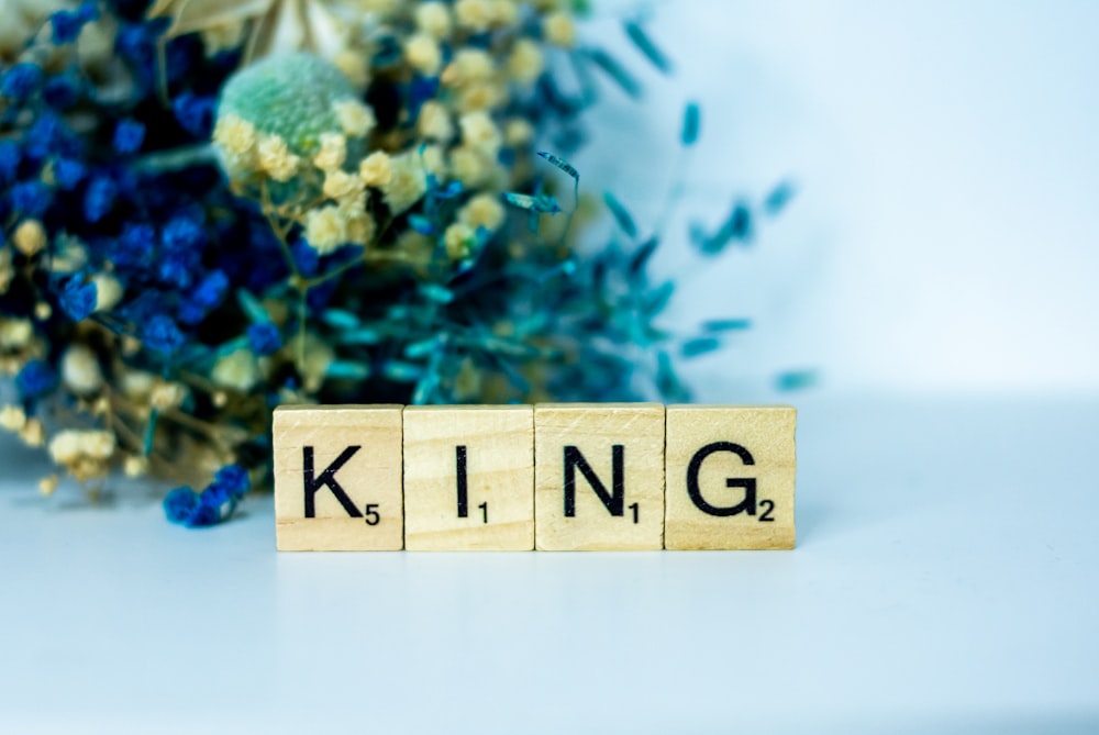 a wooden block that says king next to a bouquet of flowers