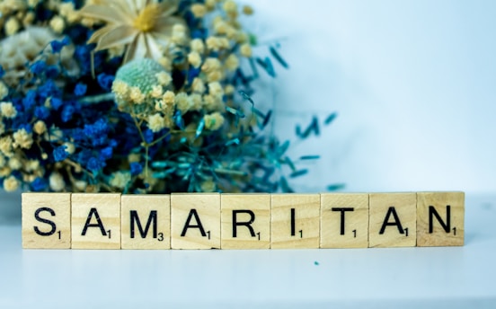 a wooden block that says samaritan next to a bouquet of flowers