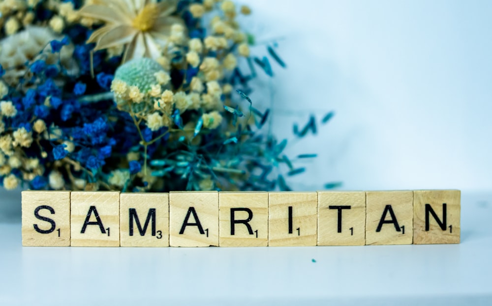 a wooden block that says samaritan next to a bouquet of flowers