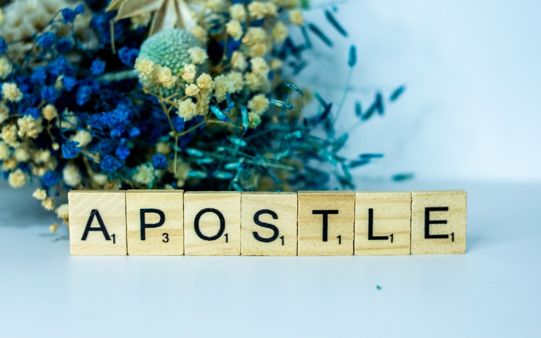 a wooden block spelling apostle next to a bouquet of flowers