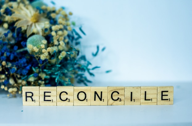 a scrabble block spelling the word reconcilie next to a bouquet