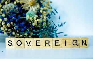 a wooden block that says sovereignn next to a bouquet of flowers