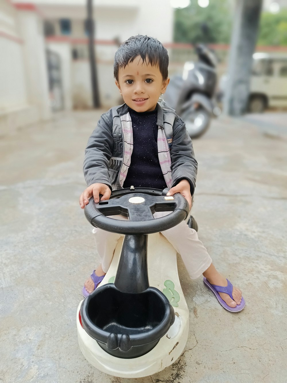 a little boy sitting on a toy car