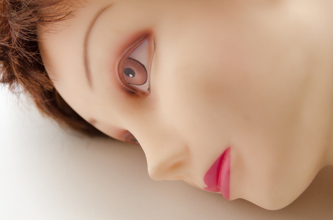 a close up of a doll's face with a pink lip