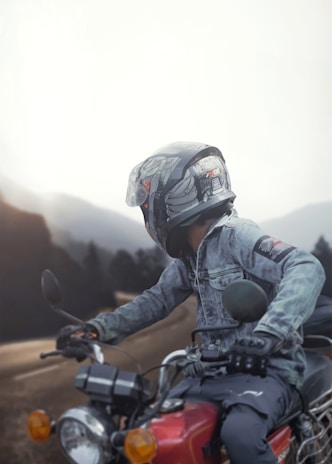 A rider wearing a bold riding jacket and gloves cruising through a scenic mountain road at sunset.