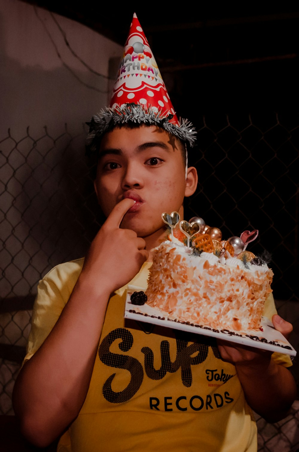 a young boy wearing a birthday hat holding a cake