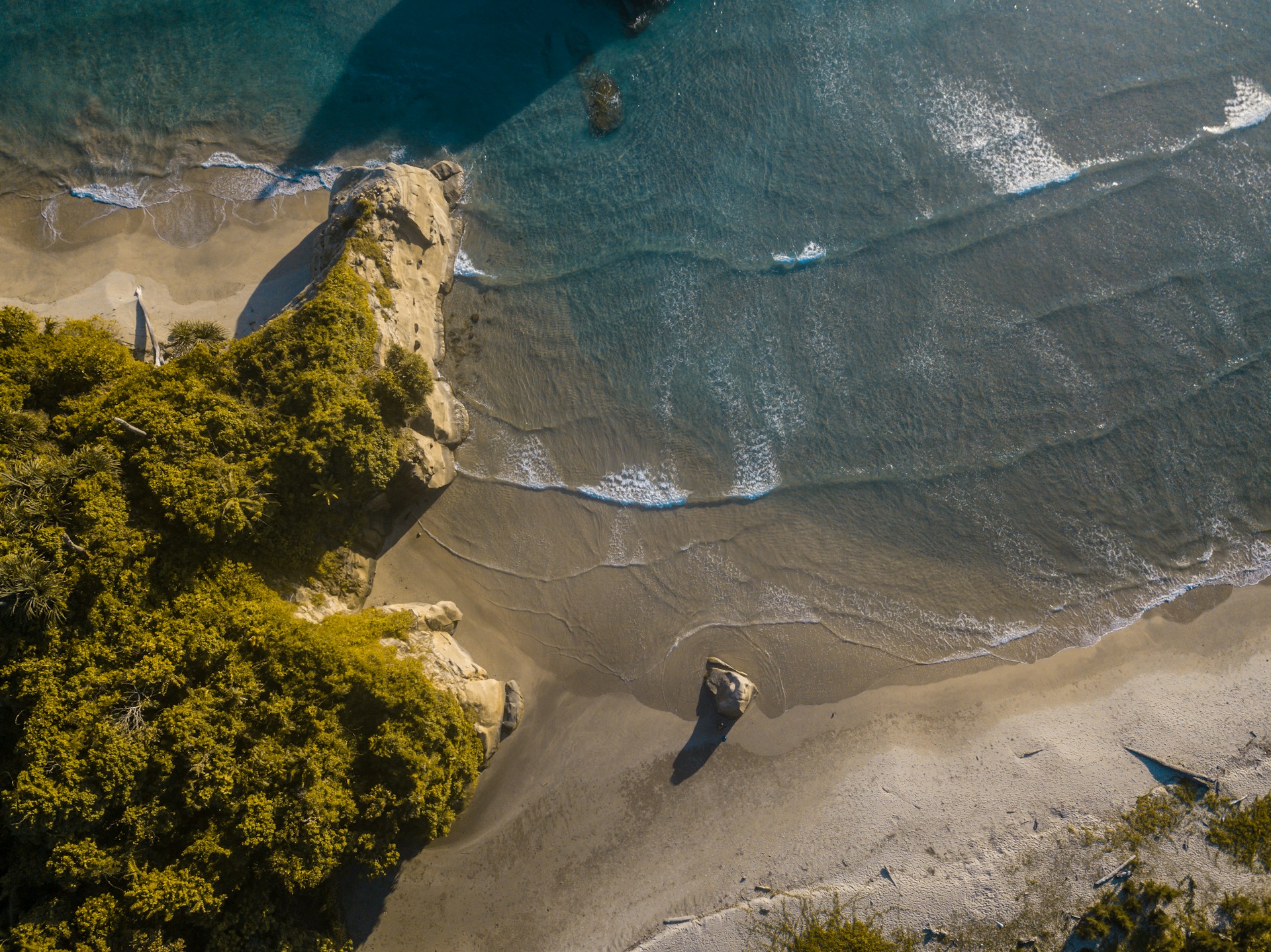 an aerial view of a beach with a boat in the water