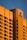 A large hotel building with a modern architectural design is bathed in warm, golden sunlight. The facade features a grid of windows and balconies, and the hotel's logo is prominently displayed at the top corner.