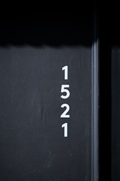 White numbers are vertically aligned on a dark gray textured wall, displaying the sequence 1, 5, 2, 1.