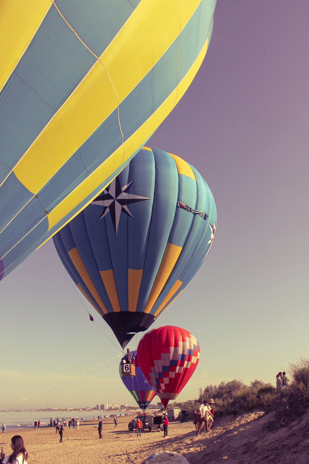 a group of hot air balloons flying over a beach