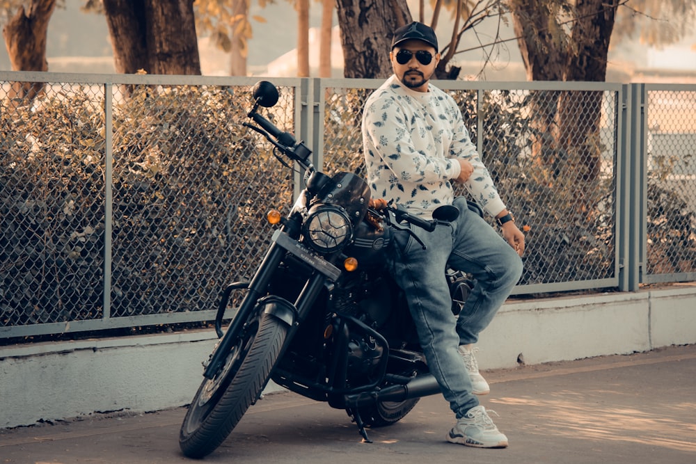 a man sitting on a motorcycle in front of a fence