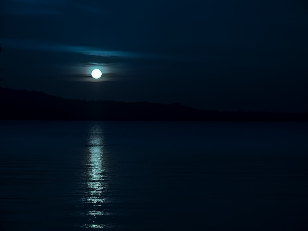 a full moon is seen over the water