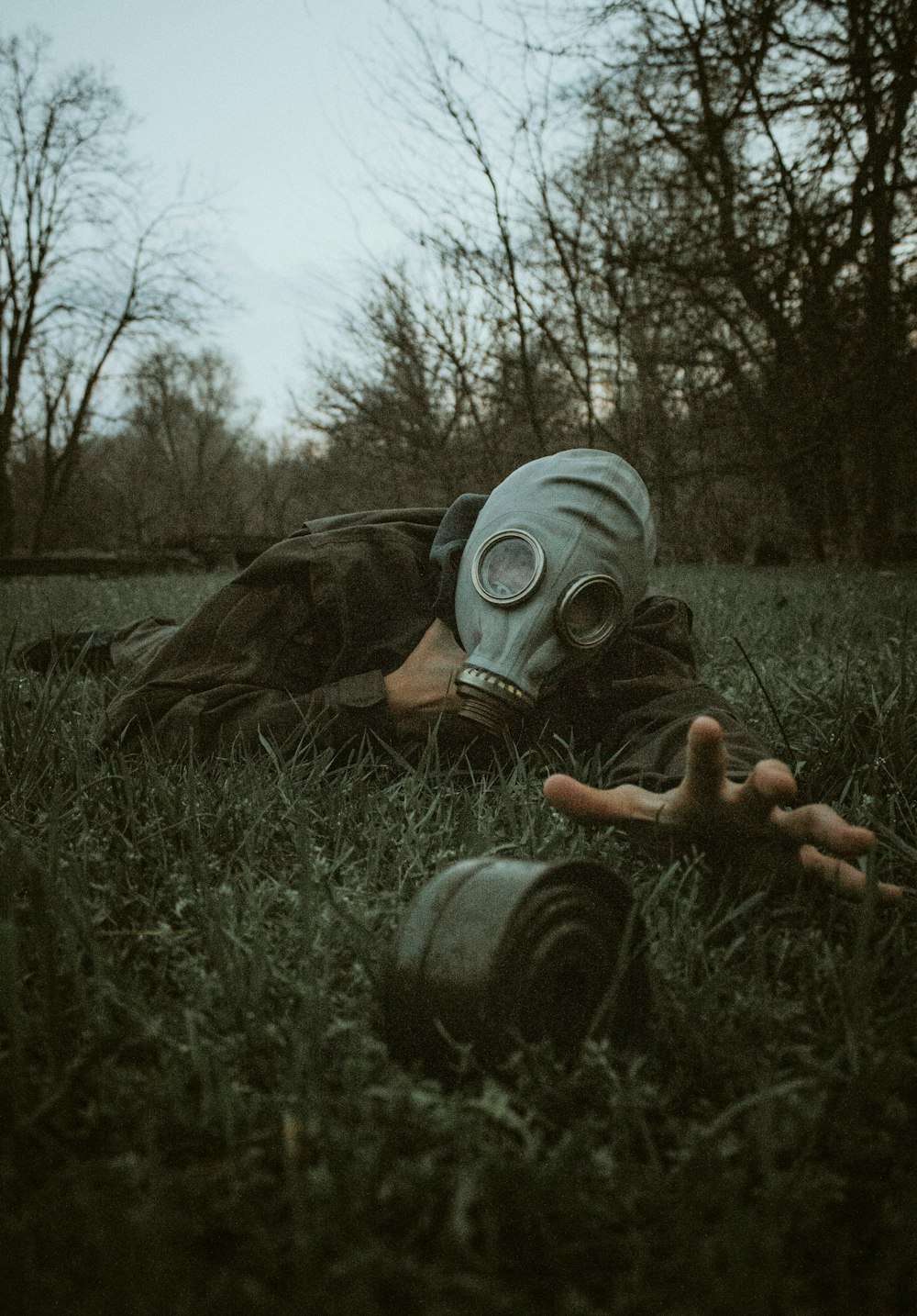 a person wearing a gas mask laying in the grass