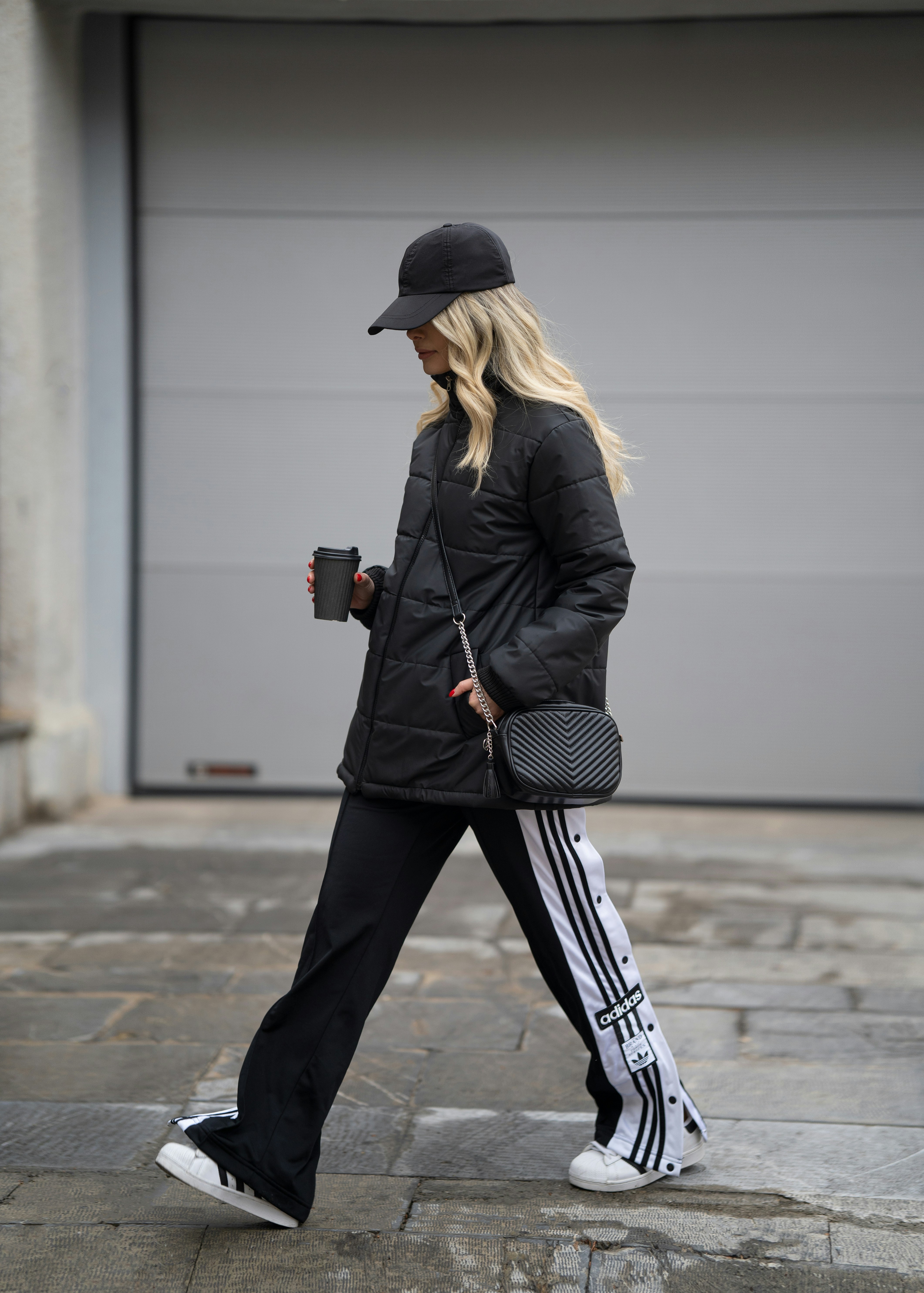 a woman walking down a street while holding a cup of coffee