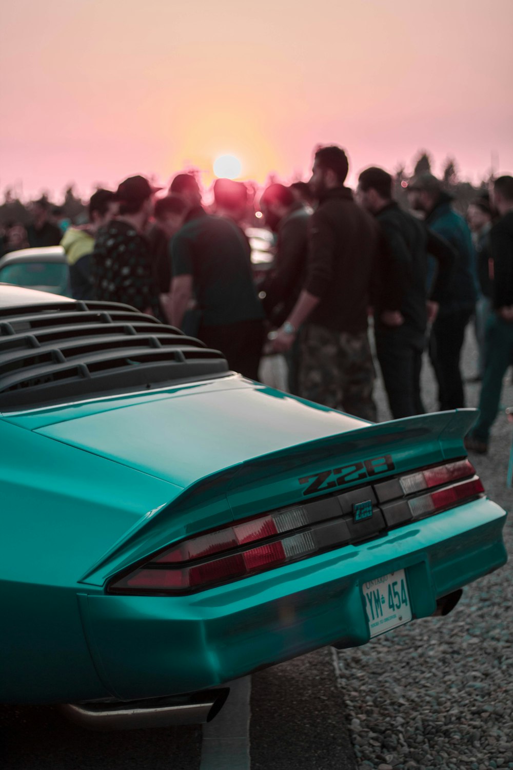 a group of people standing around a blue car