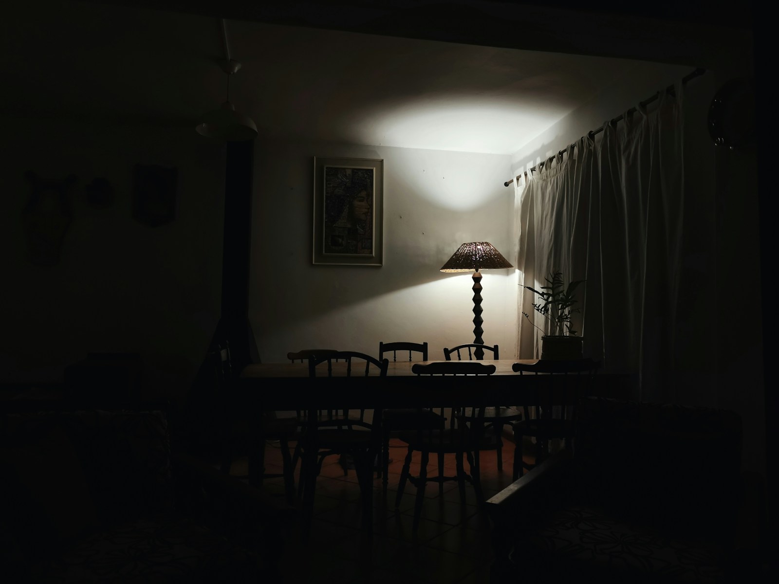 dark dining room in apartment lit only by a single warm floor lamp