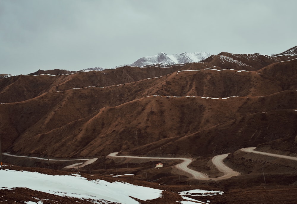 a winding road in the mountains with snow on the ground
