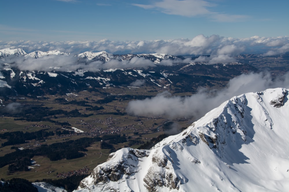 a view of a snow covered mountain with clouds in the sky