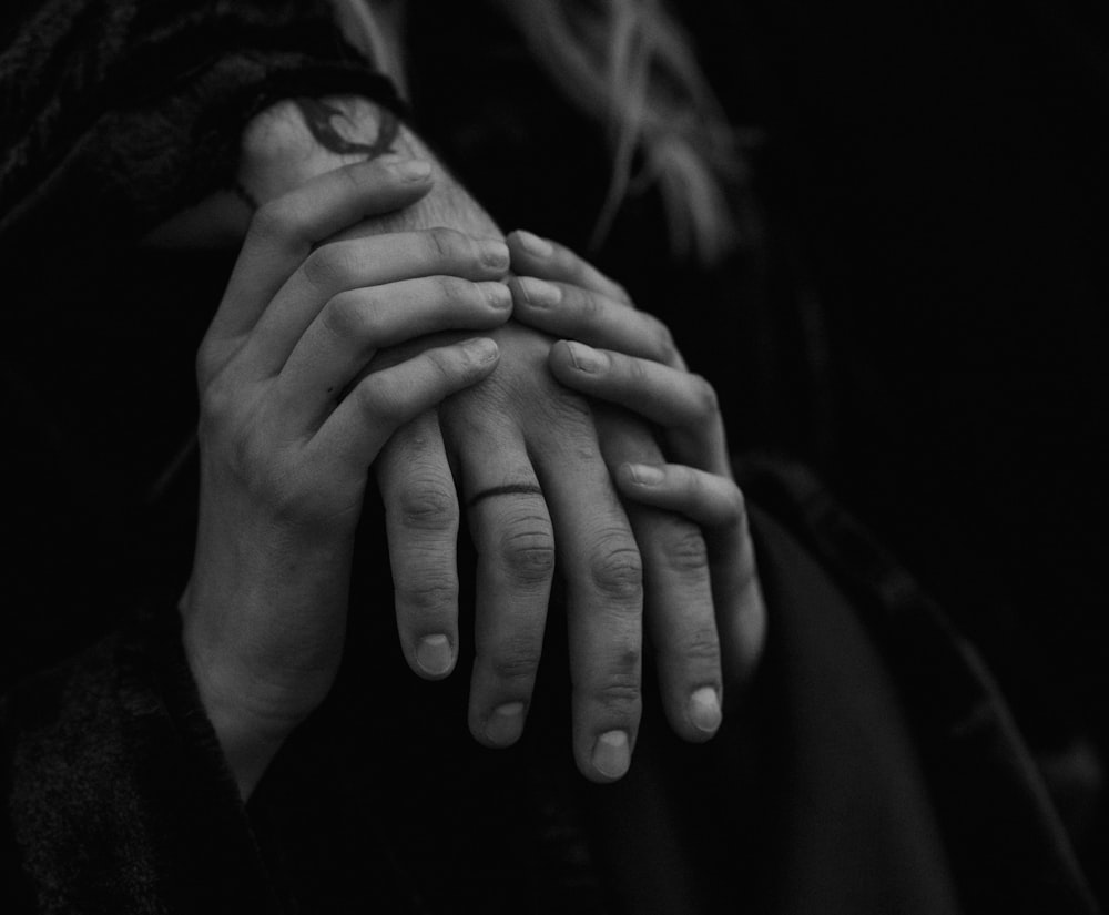 a black and white photo of two hands holding each other