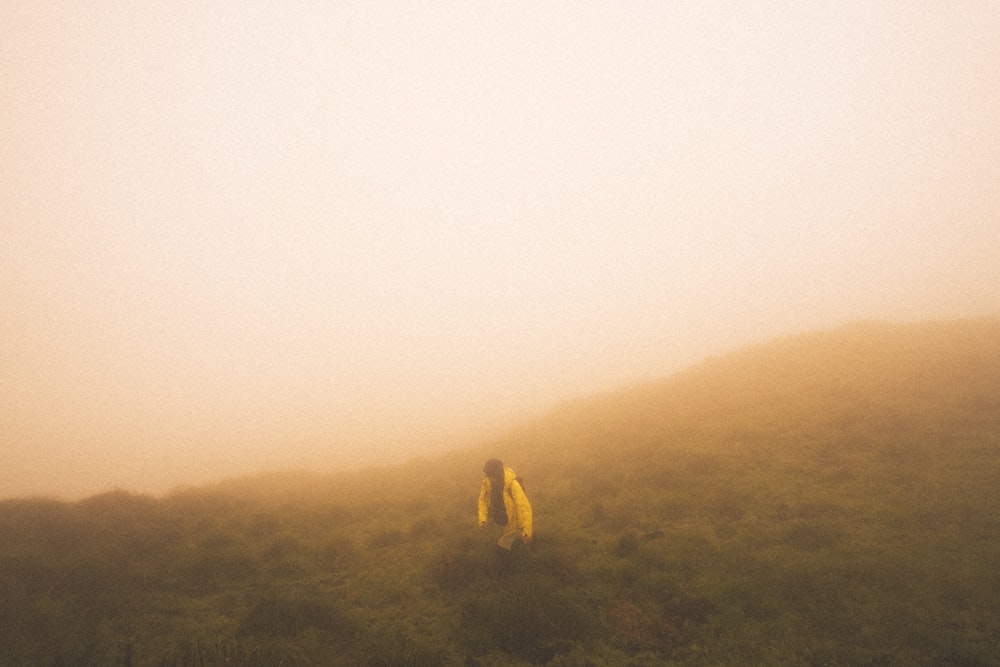 une personne qui monte une colline par temps de brouillard