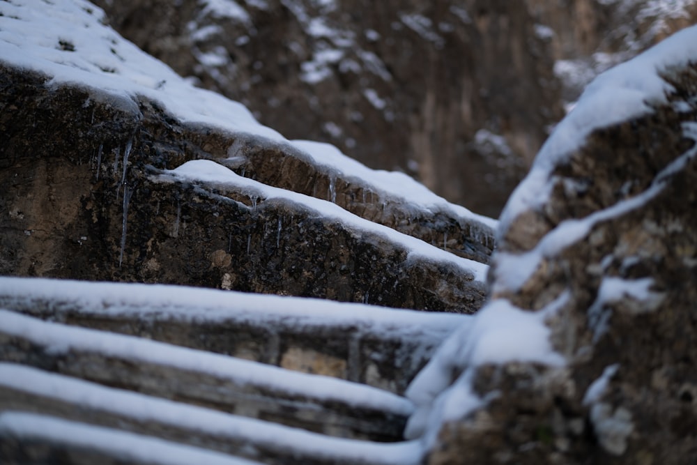 a stone wall covered in snow next to a cliff